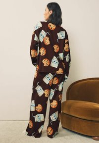 Brown loungewear set featuring a repeated print of cookies and milk cartons, with a relaxed fit and soft texture.