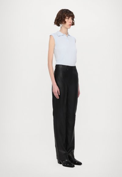 Un débardeur sans manches bleu clair, un pantalon en cuir noir taille haute et des bottes noires à talons avec des accents en métal argenté.