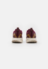 Baskets de sport bordeaux avec une tige texturée, des accents jaunes et une semelle crème mouchetée. Présente un tirant et un design de talon renforcé.