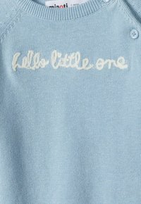 Svetlo modra pletena pulover s okroglim ovratnikom, ki ima bele vezenine z besedilom "pozdravljen mali" in modrimi gumbi kot okras na rami.