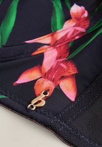 Auduma ar ziedu rakstu tumši zils fons ar rozā un oranžiem ziediem. Iekļauj zelta metāla apdari un melnu sietu detaļas apmalē.