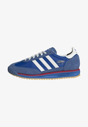 Niebieski sneaker Adidas SL 72 z białymi paskami, białymi sznurowadłami, zamszowymi nakładkami, czerwoną i niebieską podeszwą oraz złotym logo "adidas SL 72" z boku.