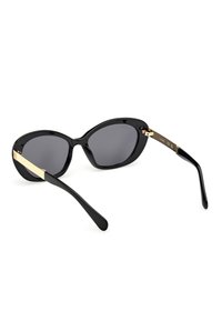 Gafas de sol negras con acabado brillante, forma ovalada, lentes oscuros y detalles dorados en las limpiaparabrisas. Diseño elegante con brazos curvados.