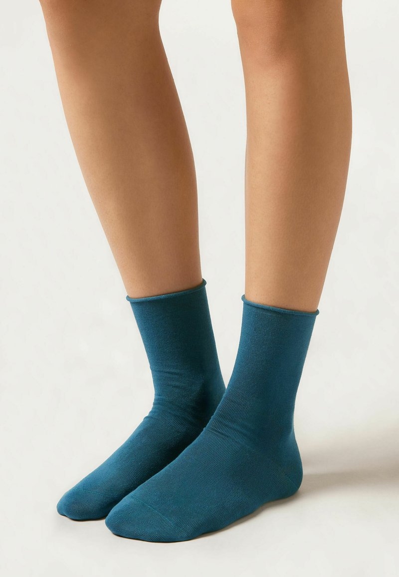Tealfärgade ankelsockor i mjukt material med ribbat benslut, som sitter åtsittande vid vristen, och har en enfärgad design utan mönster.