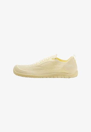 Lysebeige strikket sneaker med snørebånd, åndbart mesh-overdel, fleksibel sål og hælrem, vist i sideprofil.
