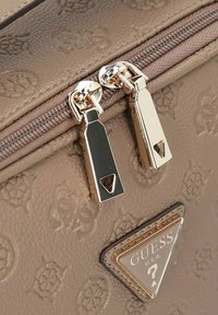 Bruine handtas van textuurmateriaal met geperste patronen, voorzien van gouden hardware en ritssluitingen. Iconisch driehoekig logo prominent weergegeven.