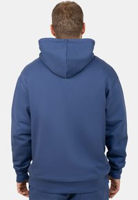 Felpa a cappuccio blu navy con vestibilità rilassata, cappuccio regolabile con cordino e polsini a costine. Realizzata in un morbido tessuto testurizzato con una finitura liscia.