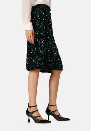 Gonna nera di paillettes con un design a lunghezza ginocchio e finitura testurizzata, abbinata a décolleté in pelle patent nera con cinturini alla caviglia.