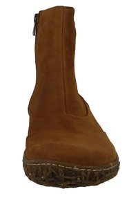 Botín de ante marrón hasta el tobillo con punta redonda, cremallera lateral, suela de goma texturizada y costura visible a lo largo del borde.