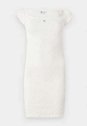 Balta, īsa, smockota kleita ar kvadrātveida kakla izgriezumu un īsām piedurknēm. Satur teksturētu audumu ar viļņotu apakšmalu. Centrālais logo akcents.