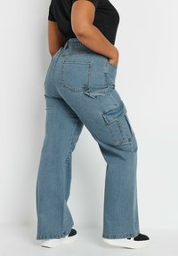 Pantalones cargo de mezclilla azul con un corte relajado, que cuentan con bolsillos laterales y bolsillos traseros tipo parche. Cintura elástica para mayor comodidad, acabado texturizado.