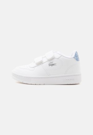 Baskets blanches Lacoste avec deux bandes velcro, un logo crocodile argenté sur le côté, et une languette de talon bleue à motifs.