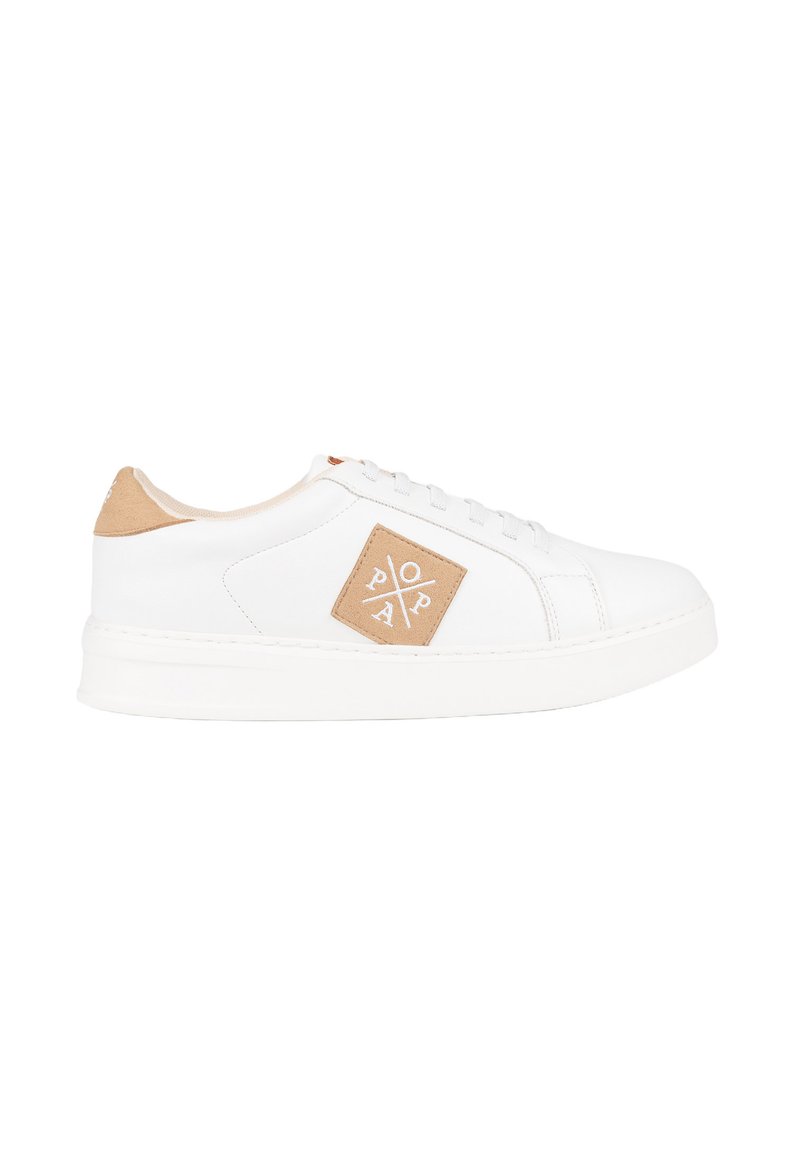 Zapatilla blanca con un exterior de cuero liso, una lengüeta de ante beige en el talón y un parche con un logo en forma de diamante en el lateral. Suela blanca plana.