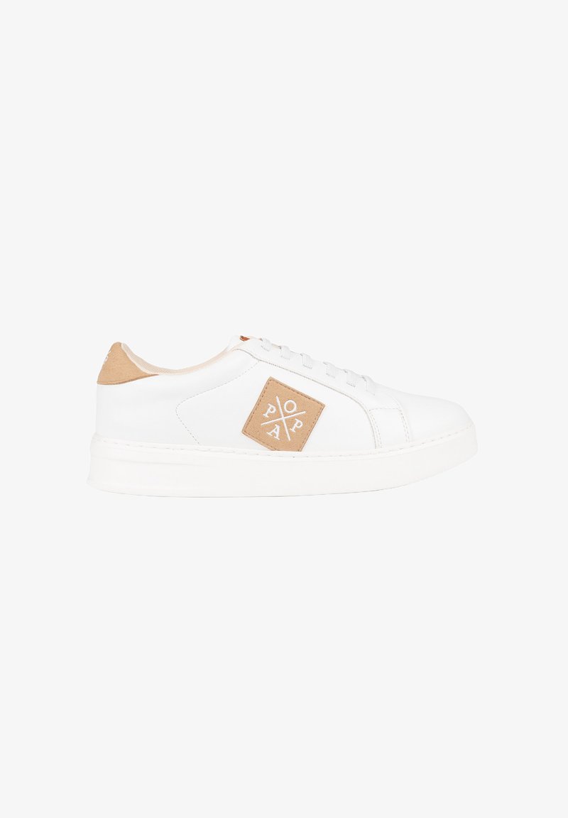 Zapatilla blanca con un exterior de cuero liso, una lengüeta de ante beige en el talón y un parche con un logo en forma de diamante en el lateral. Suela blanca plana.