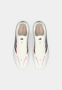 Λευκά παπούτσια ποδοσφαίρου με μαύρες και κόκκινες επισημάνσεις, αεροδυναμικός σχεδιασμός, λείος συνθετικός υλικός, που διαθέτουν διακριτική σήμανση και λογότυπο Copa.