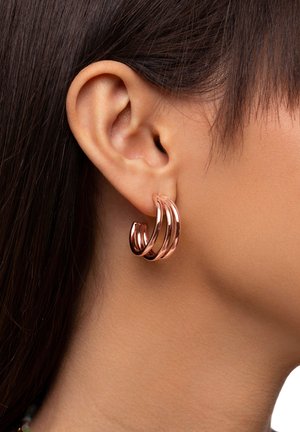 Ohrringe aus roségold mit einem spiralförmigen Design und drei miteinander verbundenen Ringen. Das Metall hat eine glänzende Oberfläche und eine glatte Textur.