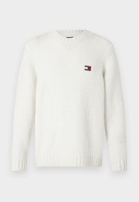 Weißer Strickpullover mit runden Halsausschnitt, gerippten Bündchen und Saum; mit einem kleinen patch in rot, weiß und blau auf der Brust.