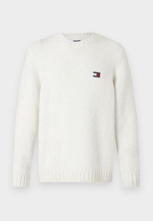 Maglione bianco lavorato a maglia con scollo rotondo, polsini e fondo a coste; presenta una piccola etichetta marchiata rossa, bianca e blu sul petto.