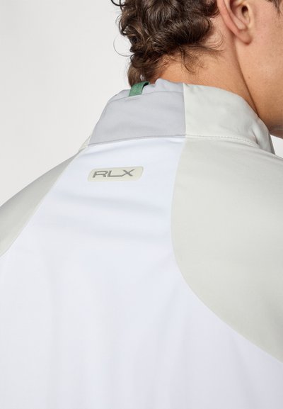 White jacket featuring gray accents, a high collar, and a green loop on the back. Displays a subtle RLX logo on the upper back. Smooth texture.