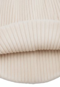 Beige geribbelde gebreide muts met een zachte textuur, voorzien van een opgerolde boord voor een verstelbare pasvorm. Gemaakt van warm, flexibel materiaal.