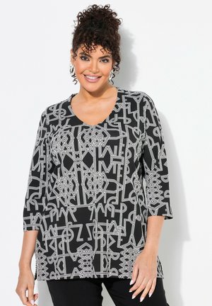 Haut noir avec motif géométrique blanc, doté d'un col en V et de manches trois quarts. Fabriqué en tissu doux et lisse.