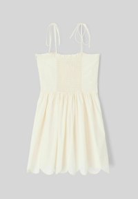 Robe d'été de couleur crème avec des bretelles spaghetti, un corsage froncé et une jupe évasée à ourlet festonné. Tissu léger.