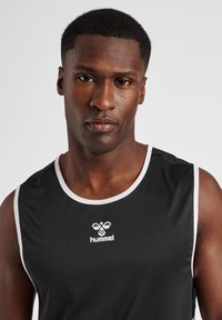 Sort ærmeløs atletisk skjorte med hvidt kantbånd, med et centralt hvidt logo "hummel" på brystet. Glat, letvægtsmateriale.