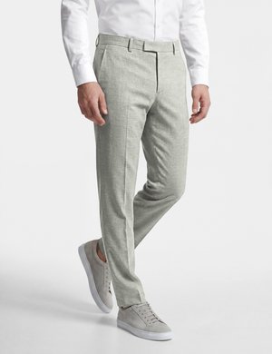 Man draagt lichtgrijze slim-fit broek, wit overhemd en lichtgrijze sneakers, staand met één been licht gebogen.