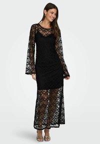 Czarna koronkowa sukienka z długimi, dzwonkowatymi rękawami i przezroczystą warstwą na wierzchu. Posiada dopasowaną, wewnętrzną warstwę oraz kwiatowy wzór na całej powierzchni.