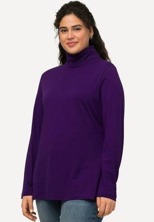 Paarse coltrui met lange mouwen, gemaakt van zachte stof, met een relaxed fit, zijsplitten en een gladde textuur. Gecombineerd met blauwe jeans.
