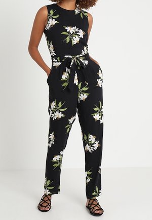 Schwarzer Blumensprunganzug mit weißen und grünen Blumenmustern, ärmelloses Design, taillierte Taille mit einem Bindegürtel und geraden Hosenbeinen.