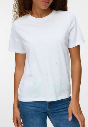 T-shirt bianco in cotone con collo a giro, maniche corte e decorazioni in tono argento sparse sul davanti, abbinato a jeans blu.