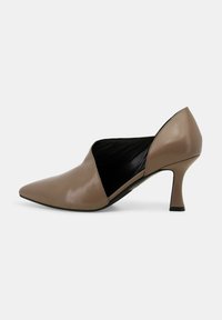 Scarpa con tacco alto a punta in pelle marrone chiaro con design a intaglio. Presenta un tacco affusolato e una texture liscia. Interno nero visibile.