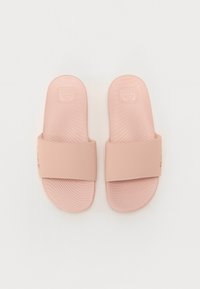 Lyse rosa slide-sandaler laget av gummi, med en bred stropp og teksturerte såler med horisontale linjer og preget merke.
