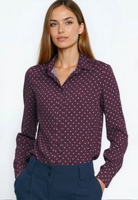 Koszula na guziki w kolorze bordowym z białymi groszkami, z klasycznym kołnierzem i długimi rękawami, zestawiona z granatowymi, wysokim stanem spodniami.