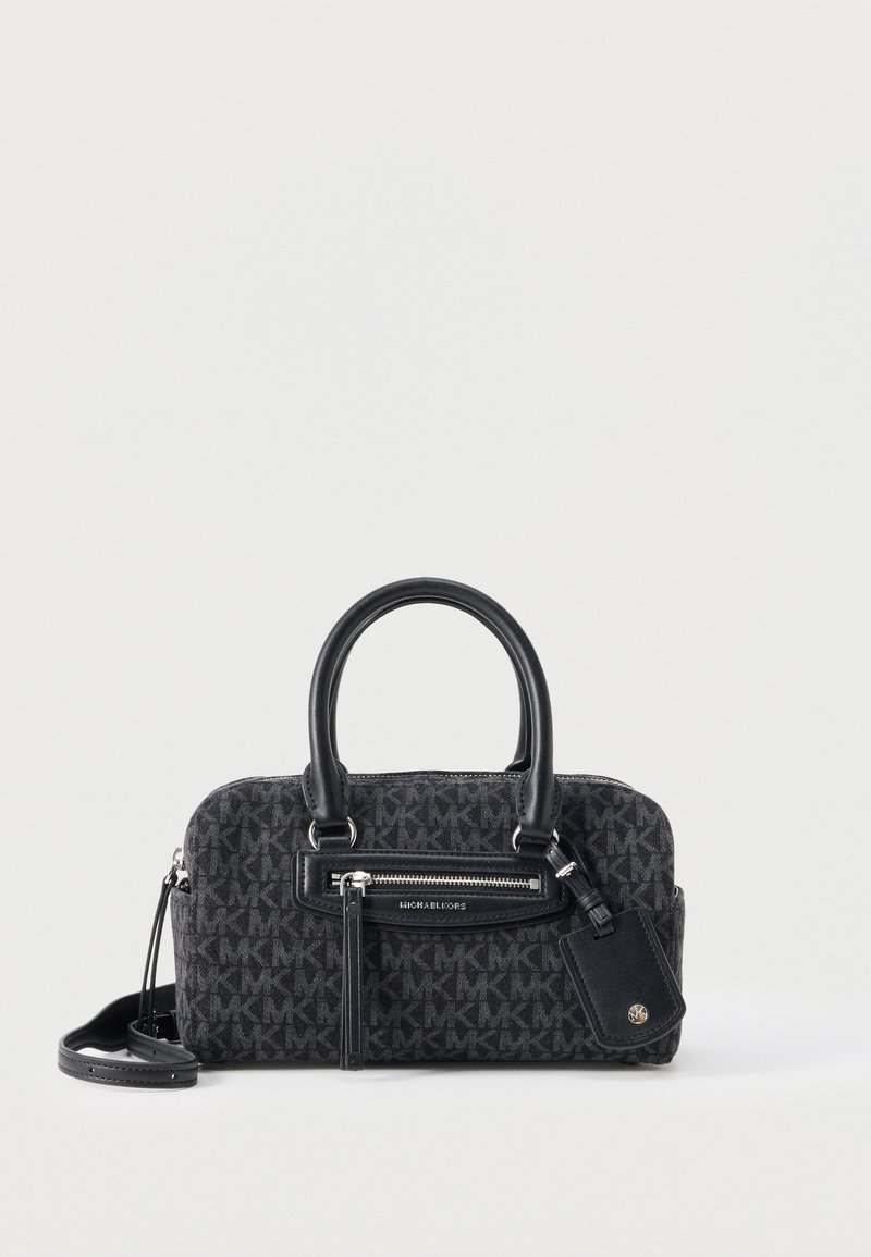 Μικρή μαύρη τσάντα χειρός Michael Kors με διπλές λαβές, μπροστινό φερμουάρ, μοτίβο με το λογότυπο MK και προσαρτημένη δερμάτινη ετικέτα σε λευκό φόντο.