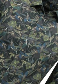 Button-up shirt met een donkere achtergrond en een multicultureel botanisch patroon van bladeren en kleine vogels, gemaakt van lichtgewicht stof.