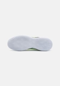 Sneaker con una suola in gomma bianca testurizzata, caratterizzata da un design superiore verde e nero. La suola ha una superficie di presa con motivo.