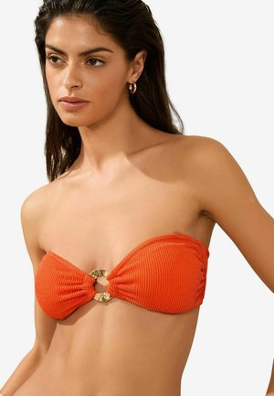 Bikini top orange en bandeau fabriqué dans un tissu texturé, présentant un détail en métal doré en forme de cercle au centre avant.