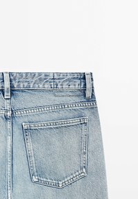 Vaaleansiniset farkut, joissa on standardikokoinen takatasku, vyölenkit ja hienovaraisesti kuvioitu vyötärönauha. Kangas on klassista tekstuuria.