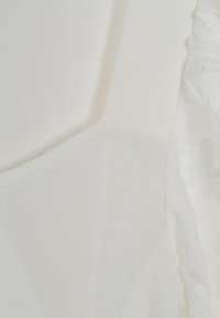 Tessuto bianco con una leggera lucentezza, caratterizzato da un motivo a maglia testurizzato e delicate decorazioni in pizzo lungo i bordi. Design pulito e senza interruzioni.