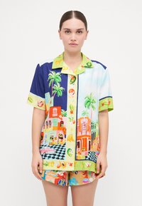 Completo di camicia a maniche corte e pantaloni corti multicolore con stampe tropicali, palme e motivi fruttati su un tessuto leggero. Colletto accentuato.