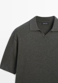 Polo en maille gris foncé à manches courtes avec col souple et petite ouverture en V, étiqueté Massimo Dutti.
