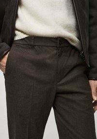Dunkelbraune, maßgeschneiderte Hosen aus strukturiertem Stoff, mit flachem Vorderteil, seitlichen Taschen und einem Knopfverschluss.