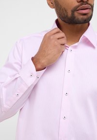 Rosa gestreifte Hemdbluse mit klassischem Kragen, perlenartigen Knöpfen und langen Ärmeln, ausgestattet mit einer subtilen, glatten Textur.