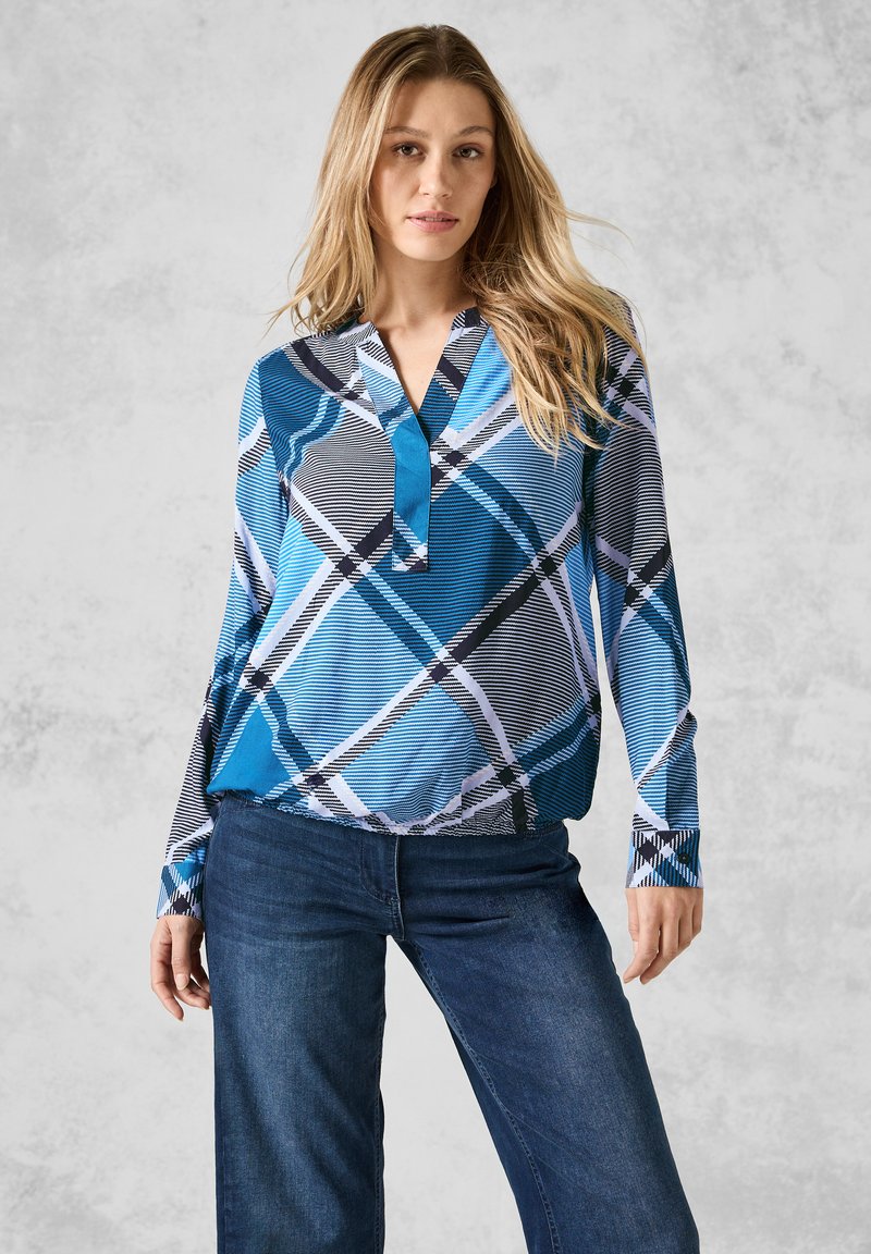 Blusa a maniche lunghe in fantasia plaid blu e nera. Presenta un collo a V e polsini a taglio, realizzata in tessuto leggero con una superficie liscia.