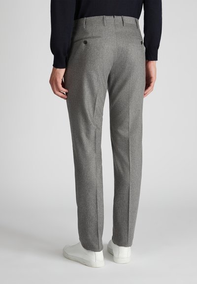 Graue maßgeschneiderte Hose aus strukturiertem Stoff, mit zwei knopfverschlossenen Gesäßtaschen und geradem Schnitt. Getragen mit weißen Sneakers.