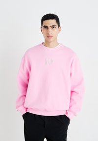 Růžová bavlněná mikina s kulatým výstřihem a spadlými rameny, na hrudi s bílým vyšitým logem "GAP".