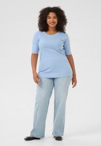 Camiseta de rayas azul claro con mangas cortas, combinada con jeans rectos azul claro y zapatos planos negros. Textura suave, ajuste casual.
