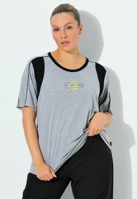 Graues T-Shirt mit schwarzen Akzenten, kurzen Ärmeln und rundem Ausschnitt. Verfügt über ein strukturiertes grafisches Design mit dem Text "LIFT, DROP, REPEAT."